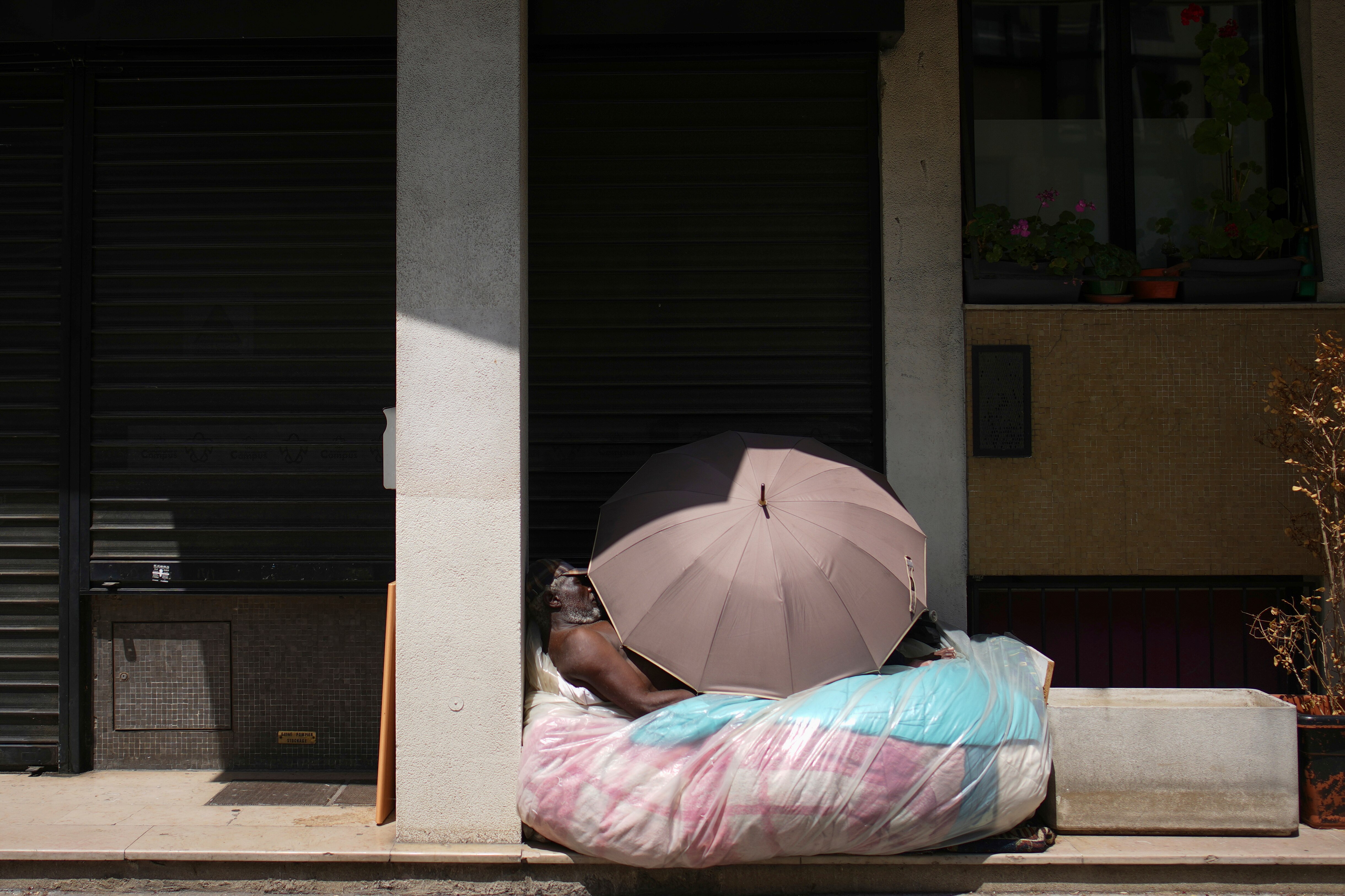 A person sleeps in the shade of his umbrella during a heat wave. (Photo: AP)