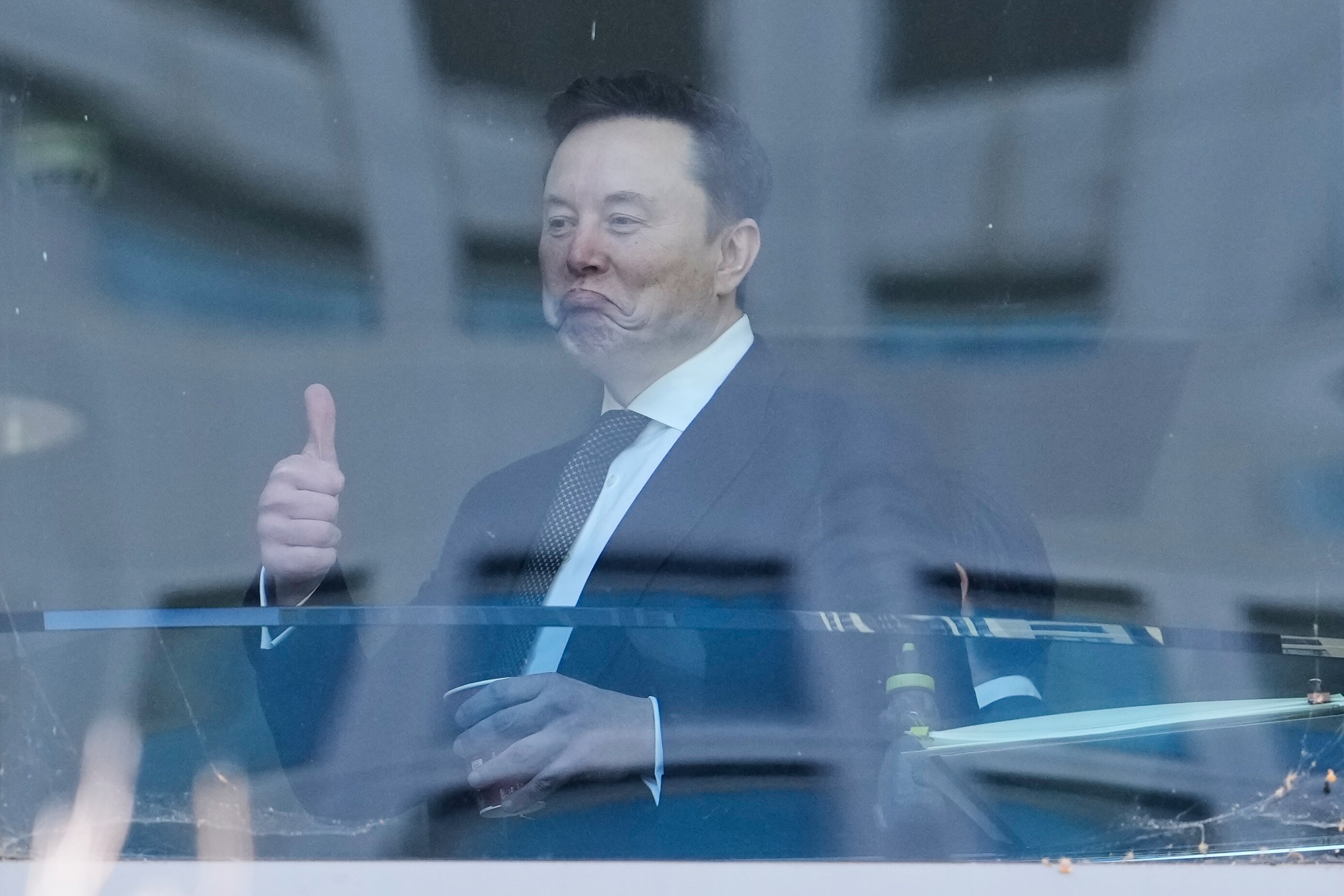 Elon Musk gestures as he walks through a hallway. (Photo: AP)