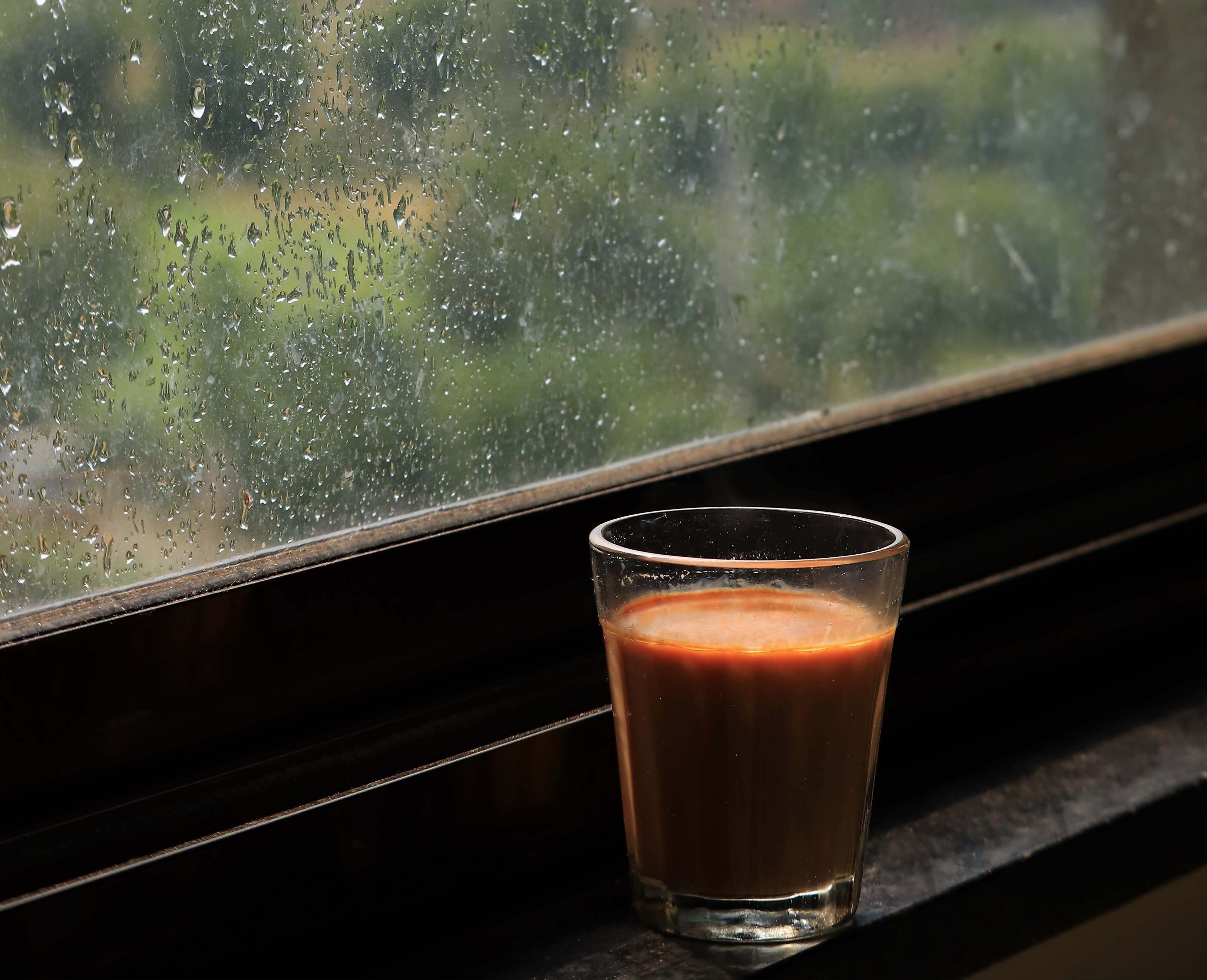A glass of chai sits beside a window as it rains outside. (Photo: Getty)