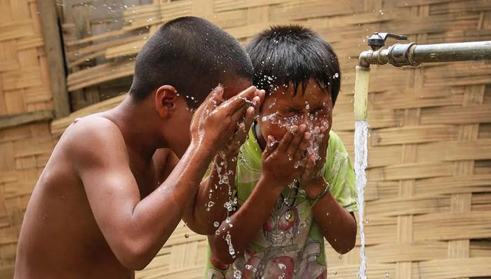 Children cooling off with piped water in a village. (Photo: Asian Development Bank)