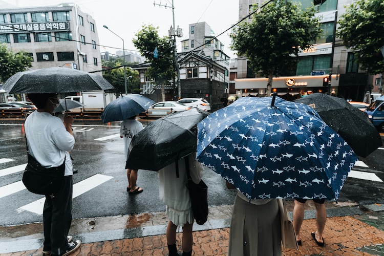 People stand with umbrellas amid heavy rain. (Photo: PTI)