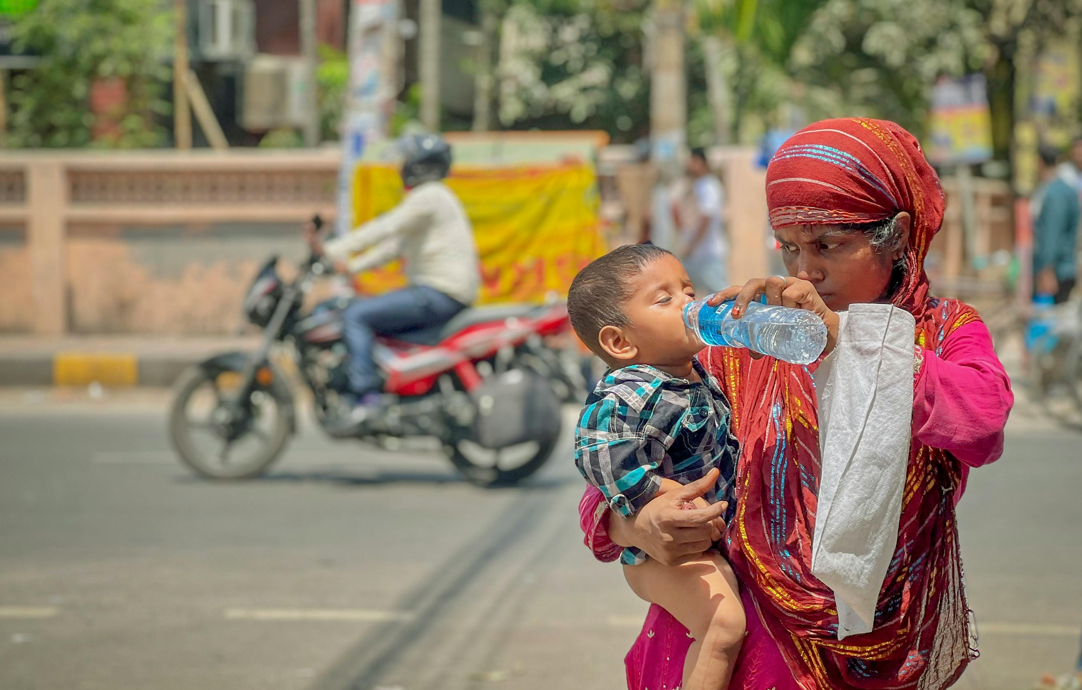 A mother gives water to her child on a hot day. (Photo: Pexels)