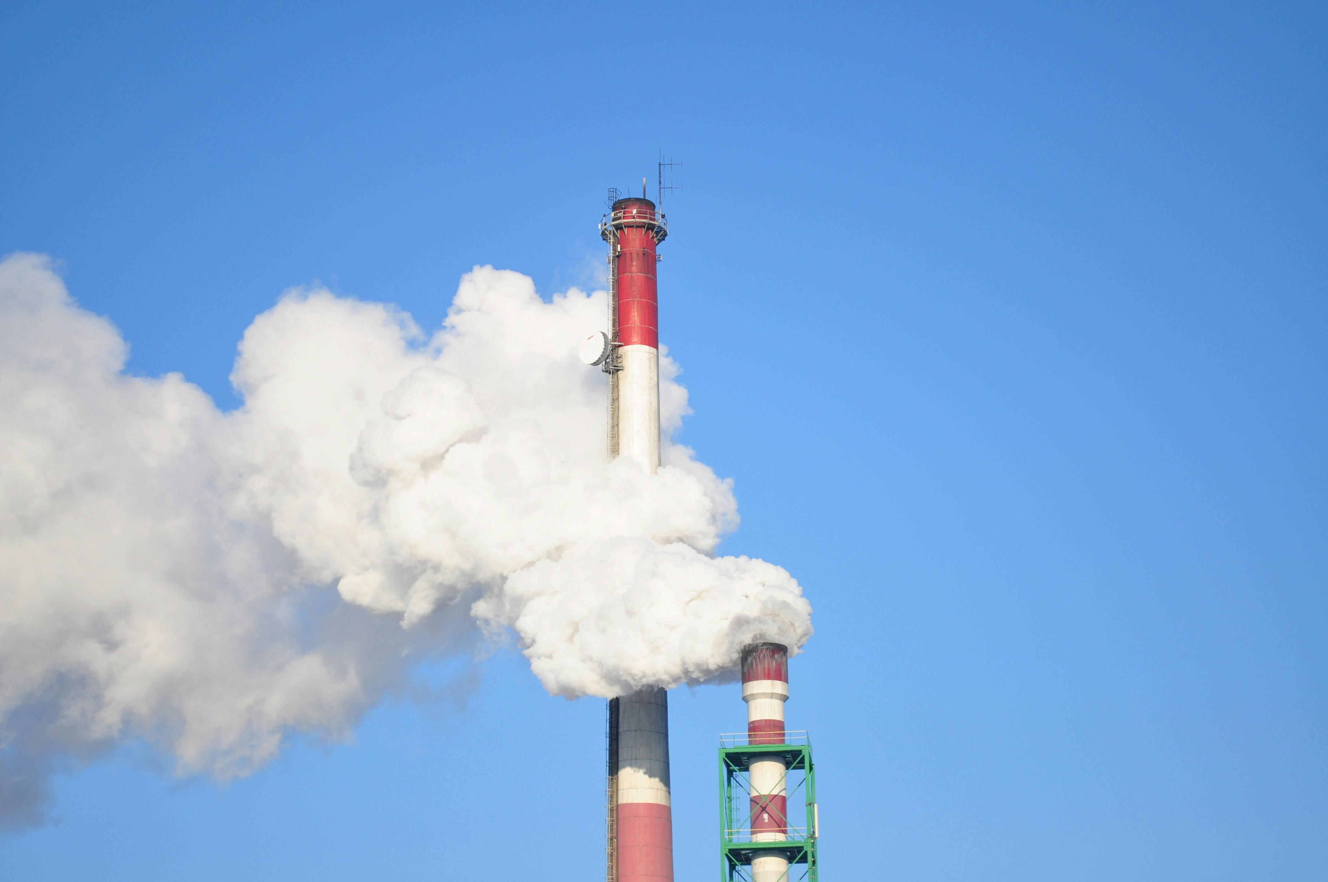 A tall industrial smokestack releasing thick white smoke. (Photo: Pexels)