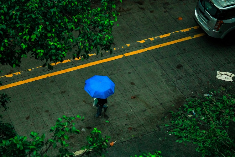 Aerial view of person with blue umbrella walking in rain in Delhi. (Photo: Pexels)