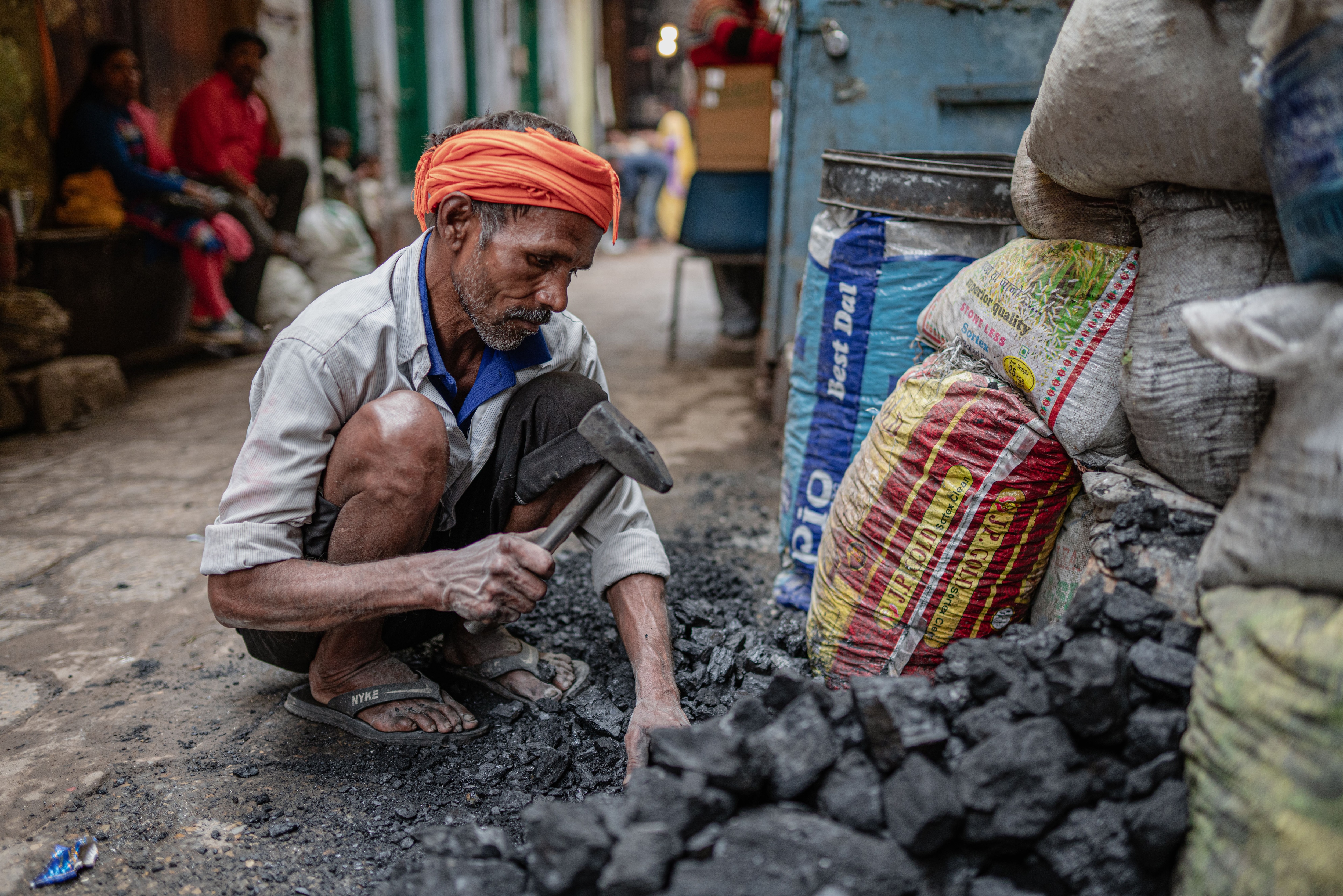 An elderly man sorts coal for sale. (Photo: Pexels)