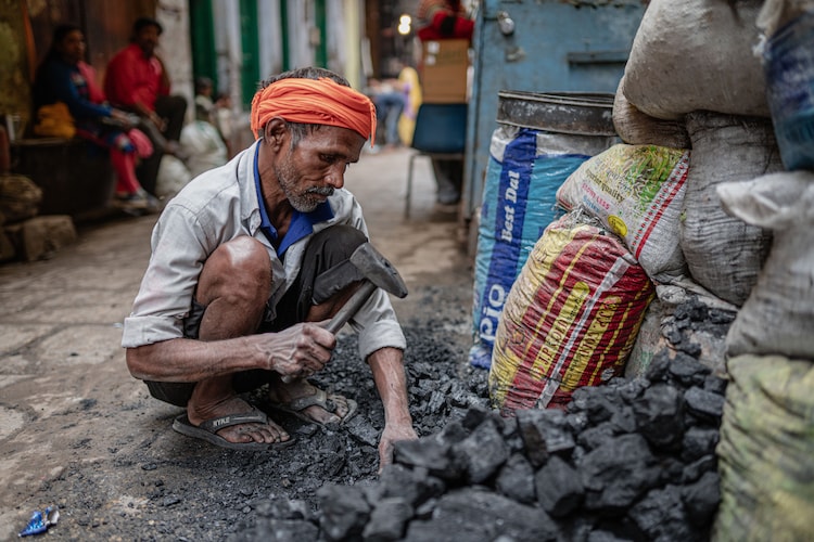 An elderly man sorts coal for sale. (Photo: Pexels)