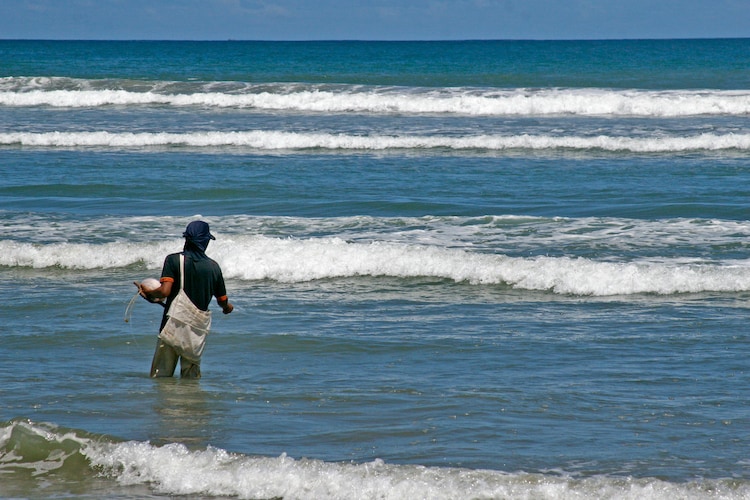 A man fishing in ocean waves. (Photo: Pexels)