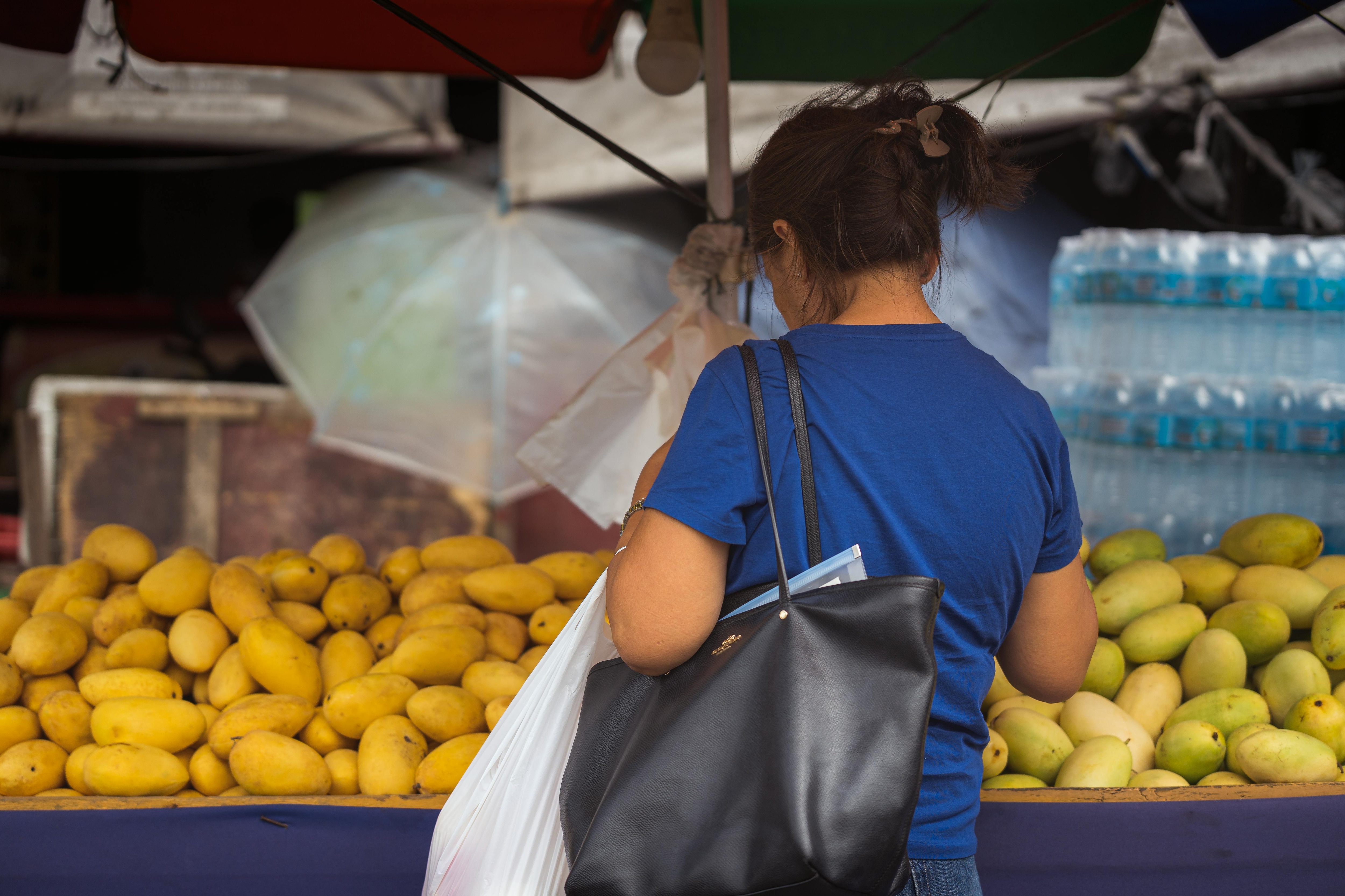 A woman buying fresh mangoes at a local market. (Photo: Pexels)