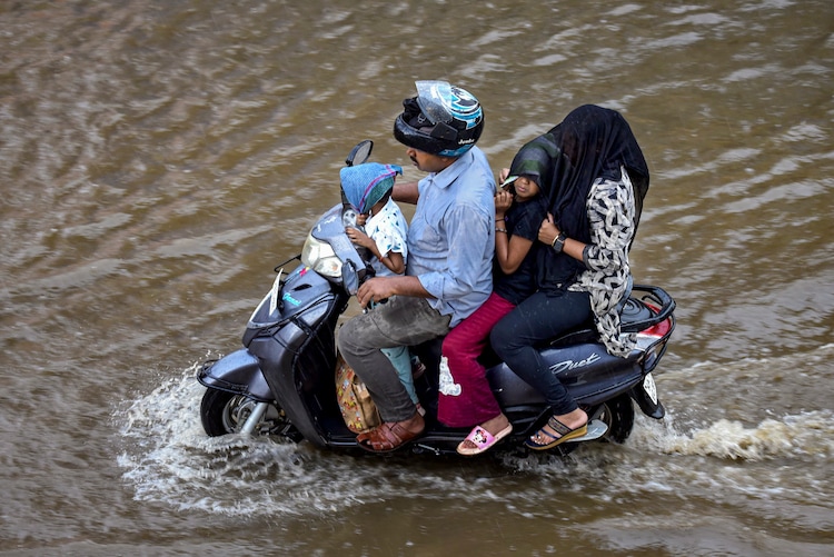 Commuters wade through a flooded road. (Photo: PTI)