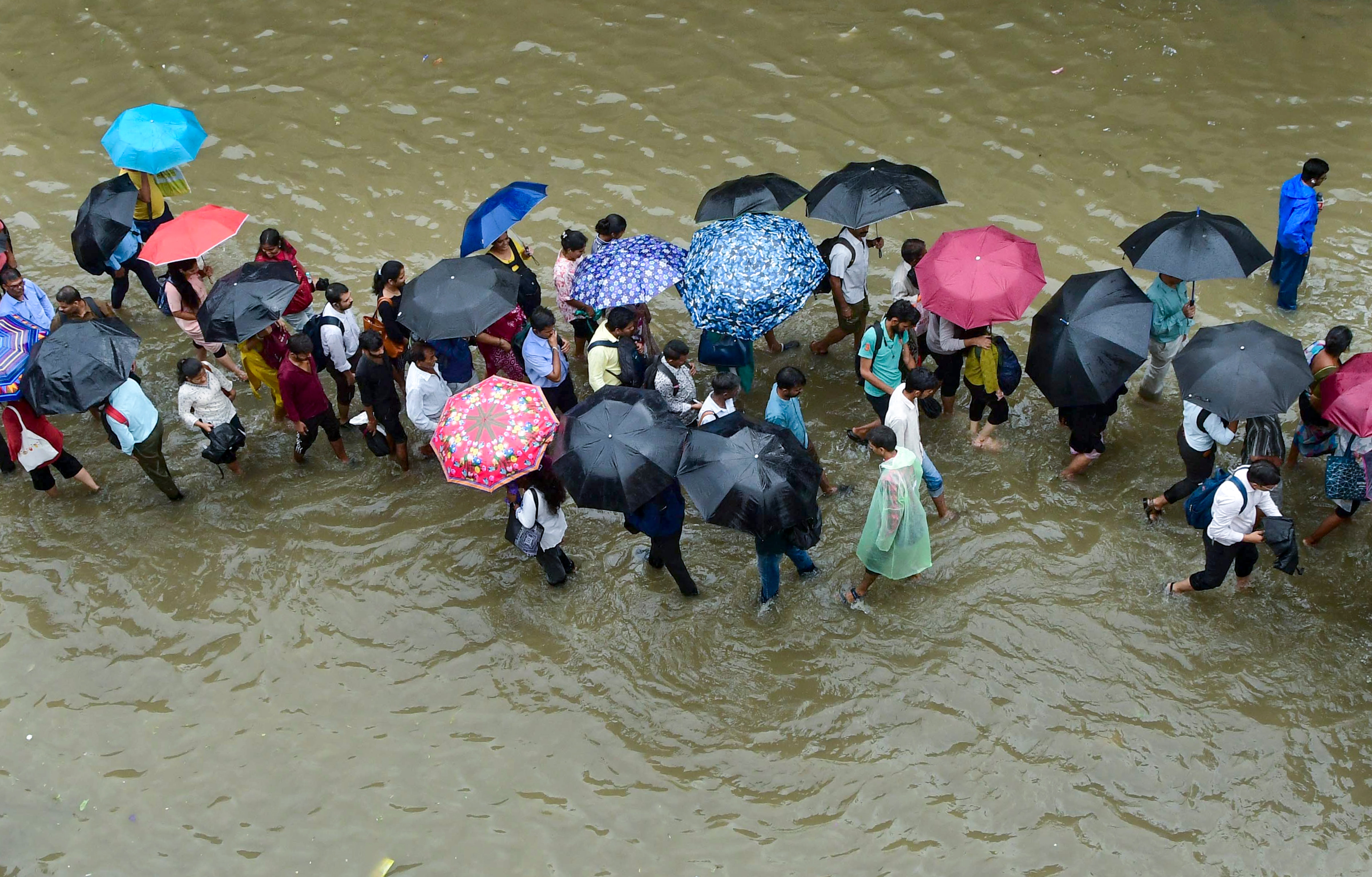 Commuters wade through a waterlogged street after heavy rain in Mumbai. (Photo: PTI)