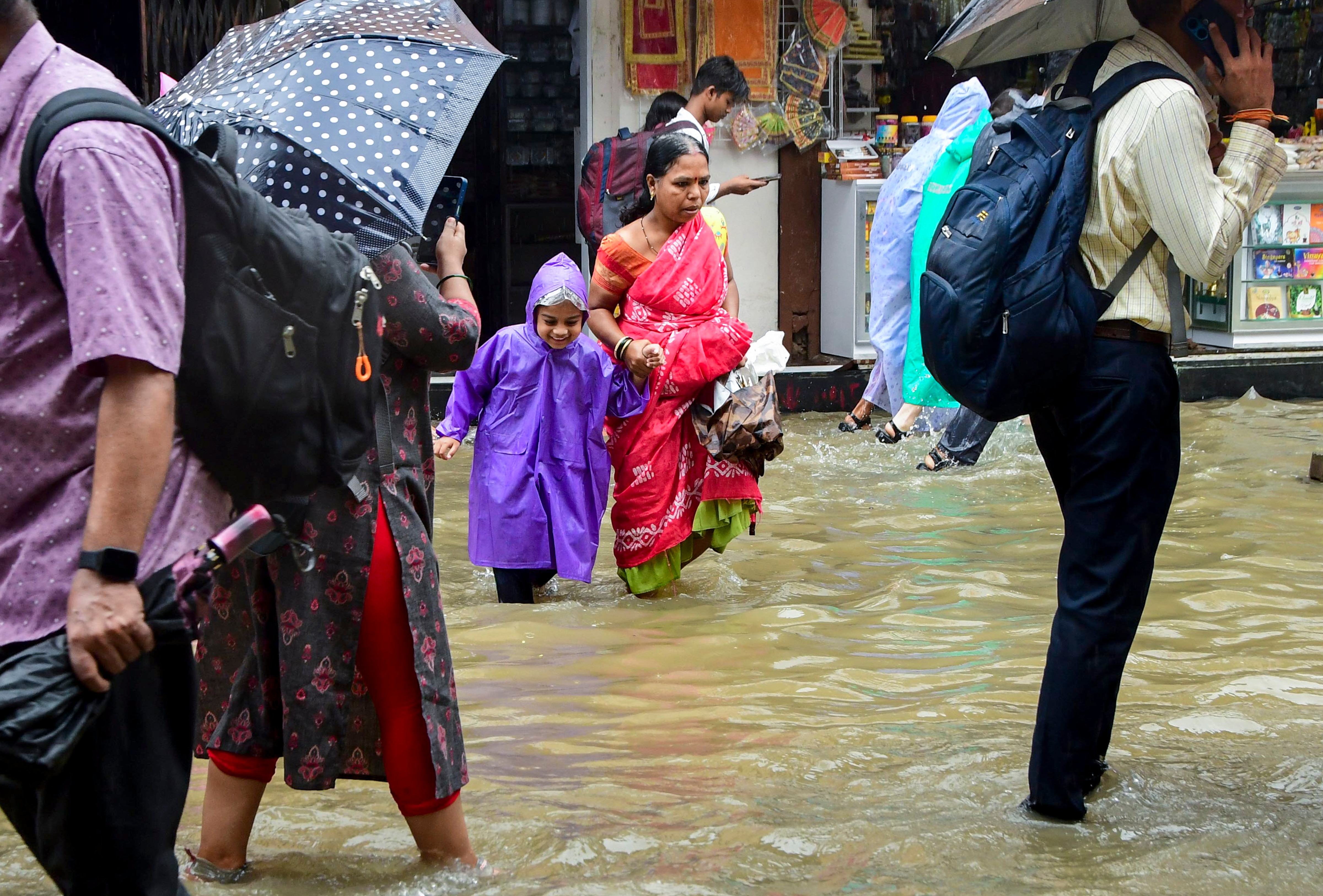 Commuters wade through a waterlogged street after heavy rain, in Mumbai. (Photo: PTI)