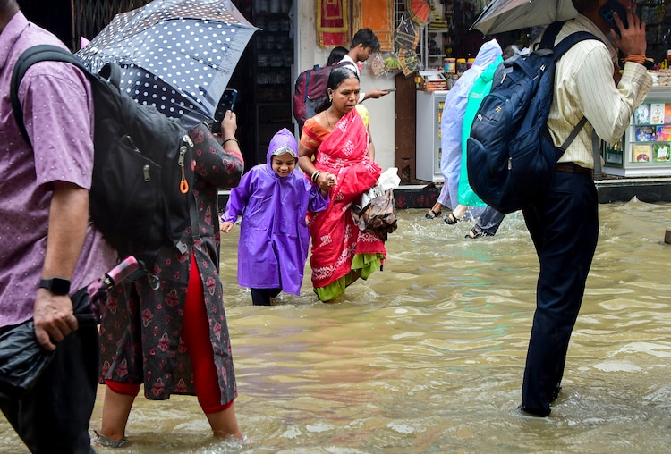 Commuters wade through a waterlogged street after heavy rain, in Mumbai. (Photo: PTI)
