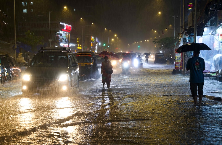 Commuters move through a waterlogged road amid heavy rain in Mumbai (Photo: PTI)
