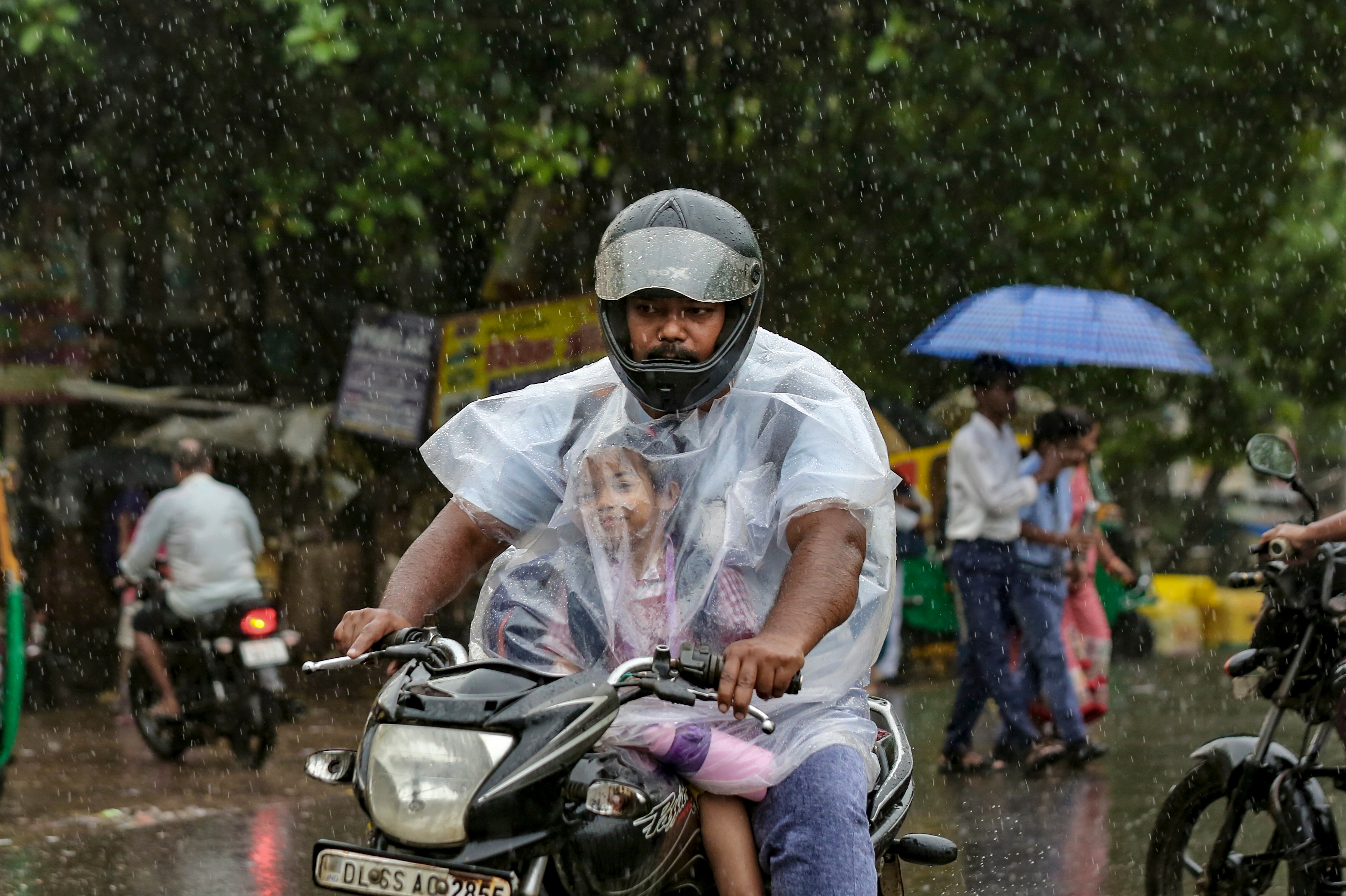 A man and a child drive through heavy rain in New Delhi. (Photo: PTI)