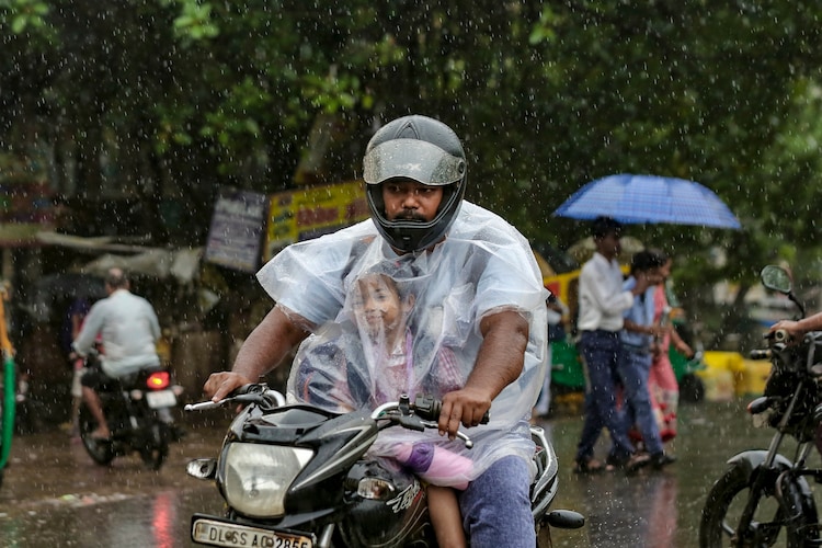 A man and a child drive through heavy rain in New Delhi. (Photo: PTI)