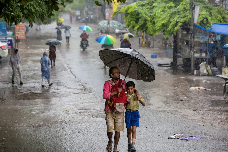 A man and his child walk amid heavy rain in New Delhi. (Photo: PTI)