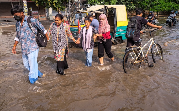 People wade through a waterlogged street in Gurugram. (Photo: PTI)