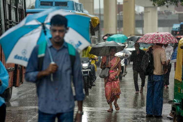People are seen walking amid rain. (Photo: PTI)
