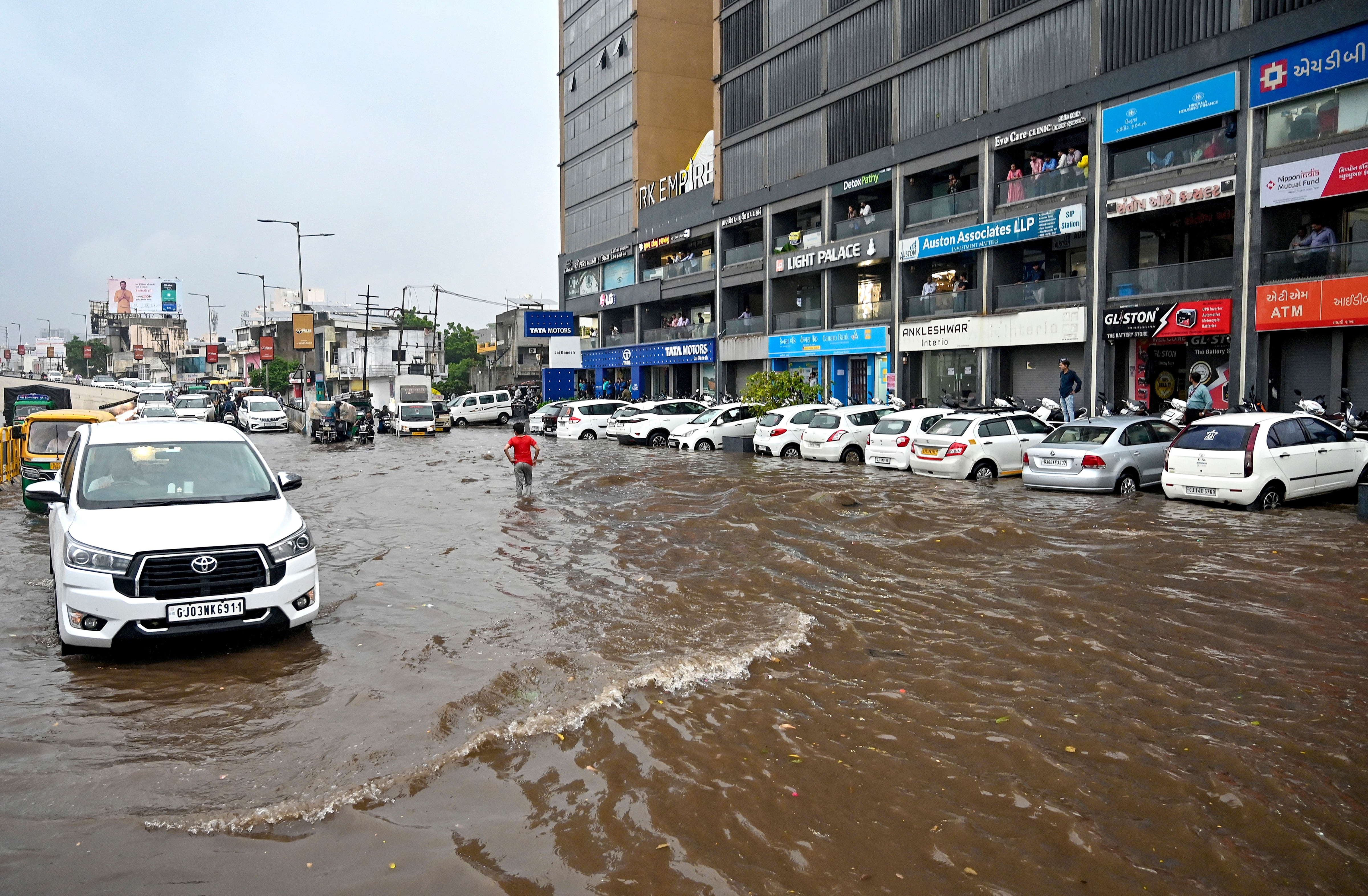 Commuters make their way on a waterlogged road after heavy rain, in Rajkot. (Photo: PTI)