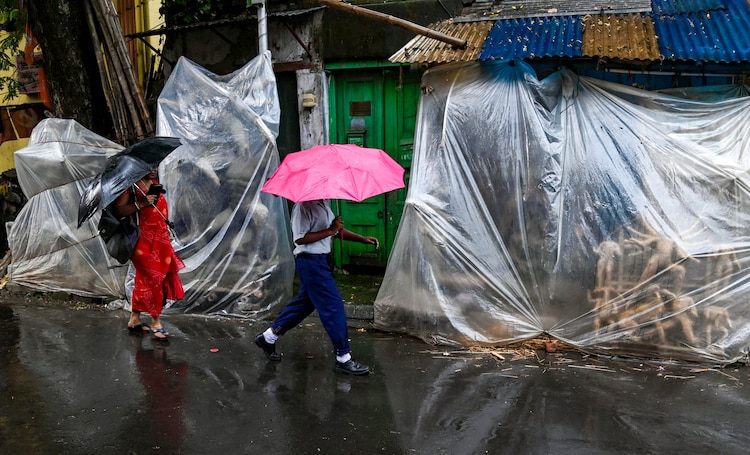 People walk through rain with umbrellas. (Photo: PTI)