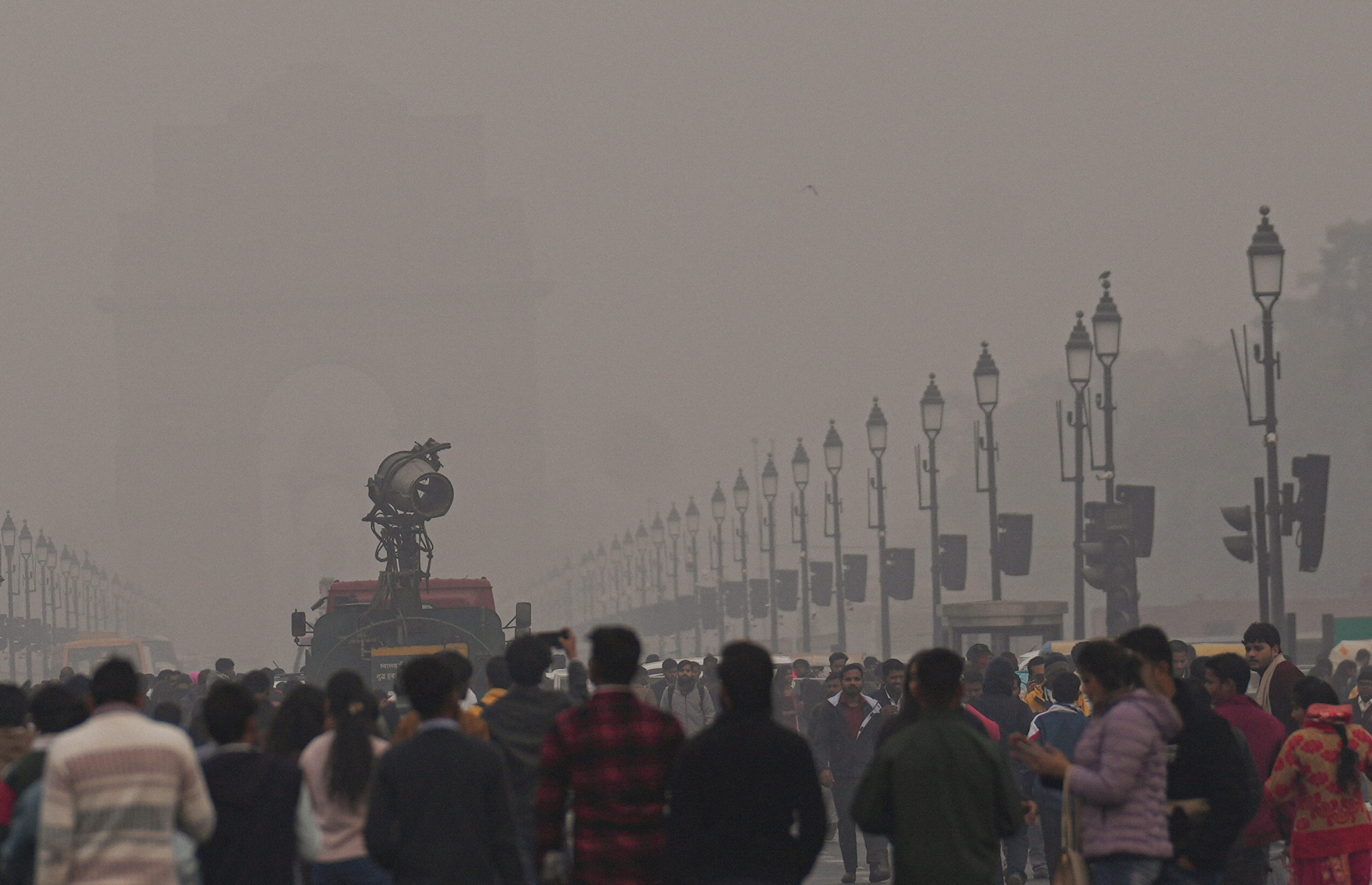 An anti-smog gun being used to curb air pollution as people visit the India Gate. (Photo: PTI)