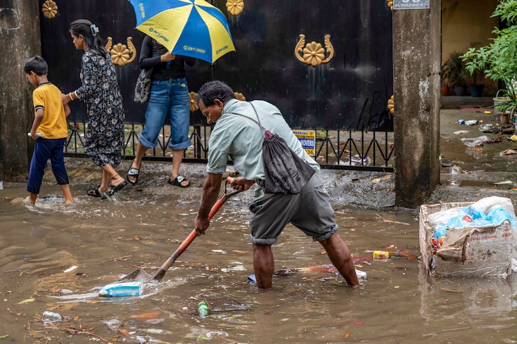 A man clears debris from a clogged drain following rainfall, in Guwahati, Assam. (Photo: PTI)
