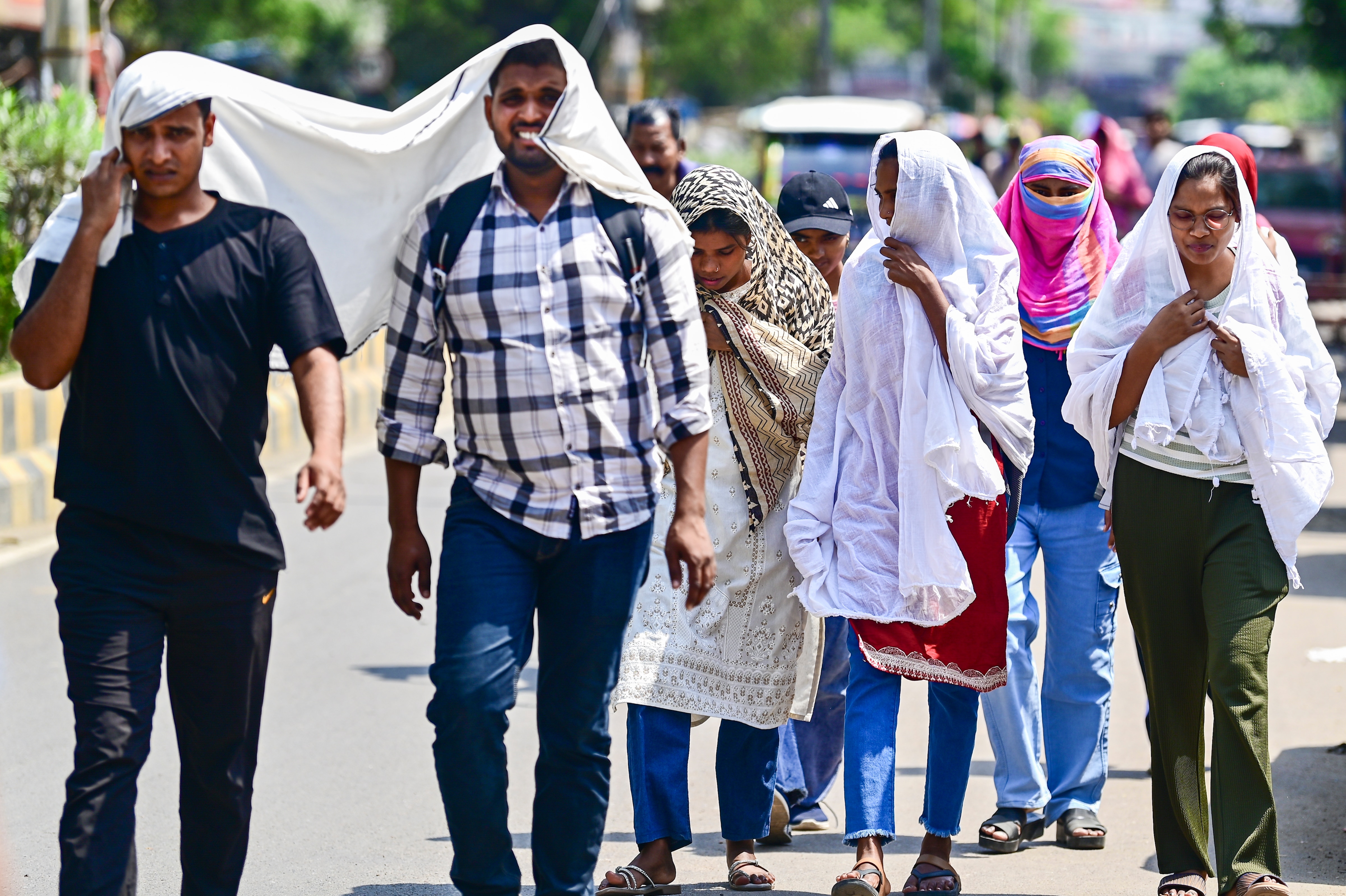 People walk while shielding themselves from the heat in Prayagraj. (Photo: PTI)