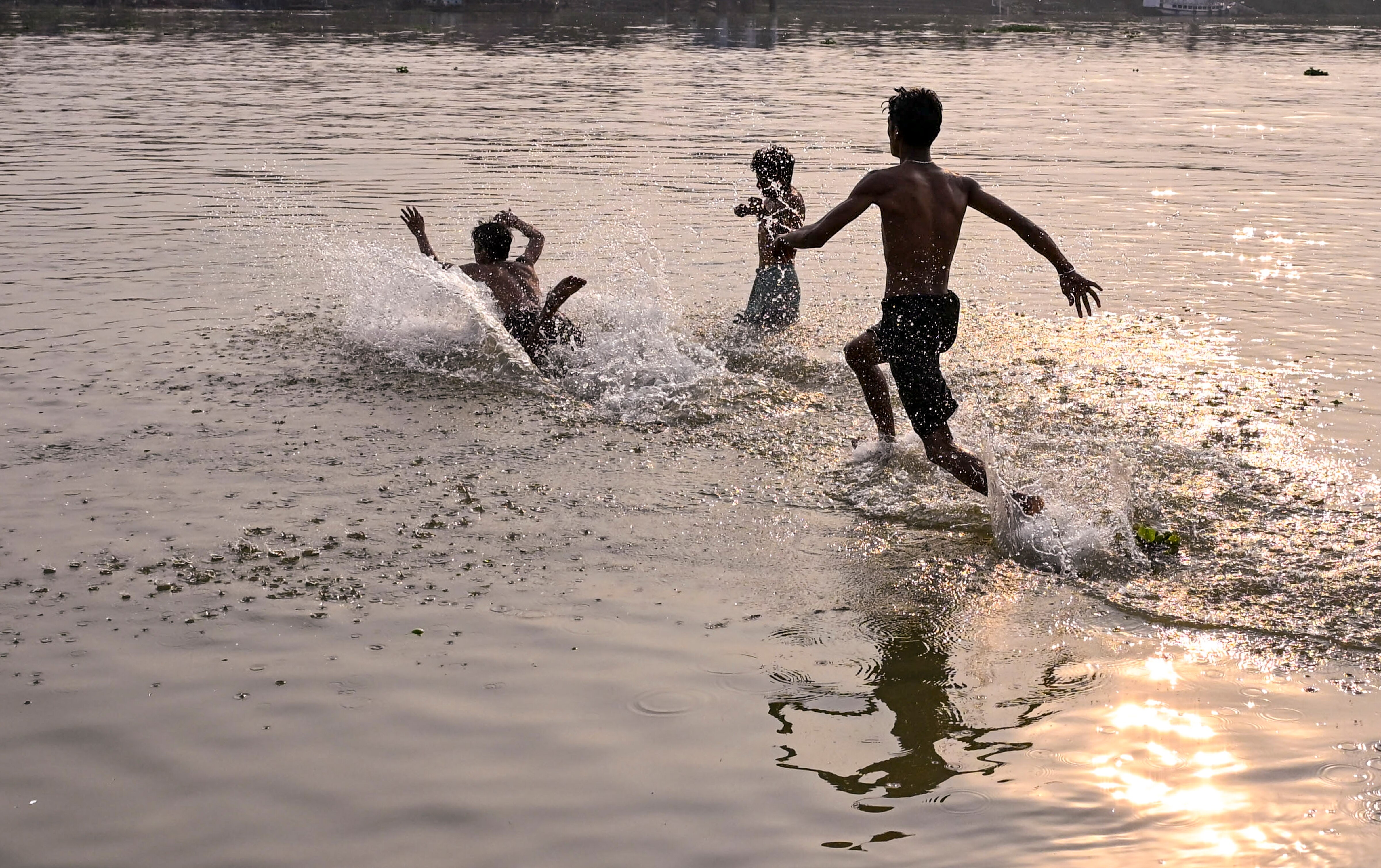 Young boys beat the heat by playing in a waterbody in West Bengal. (Photo: PTI)