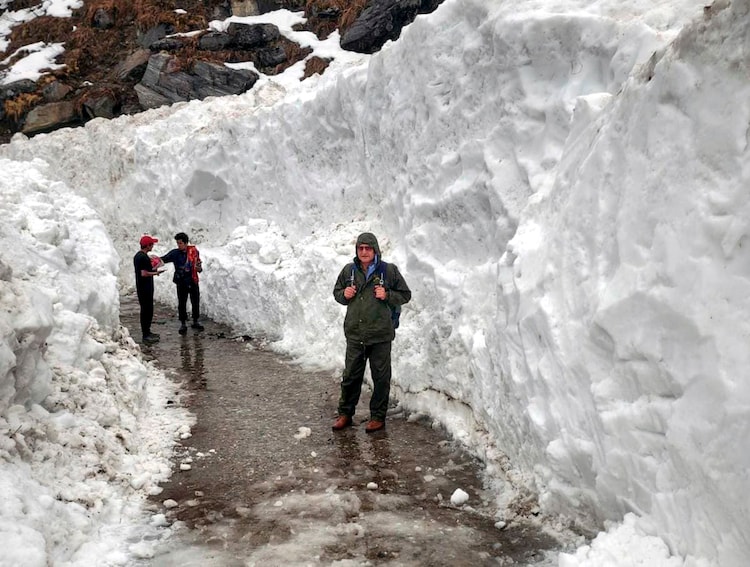 People walk along a snow-cleared path amid heavy accumulation following fresh snowfall near Kedarnath Dham. (Photo: PTI)