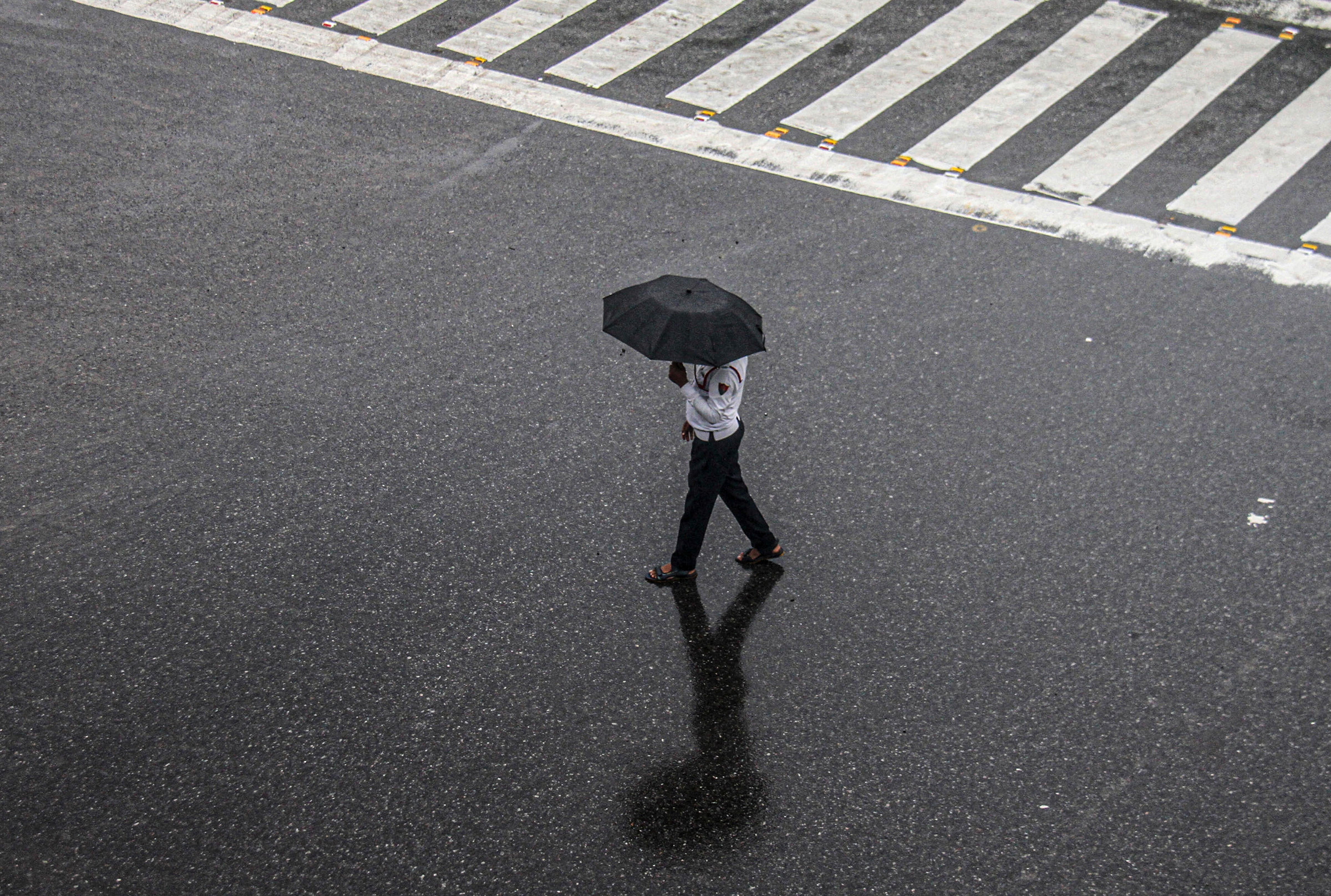A traffic police official walks across a road during rain, in Gurugram, Haryana. (Photo: PTI)
