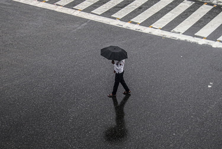 A traffic police official walks across a road during rain, in Gurugram, Haryana. (Photo: PTI)