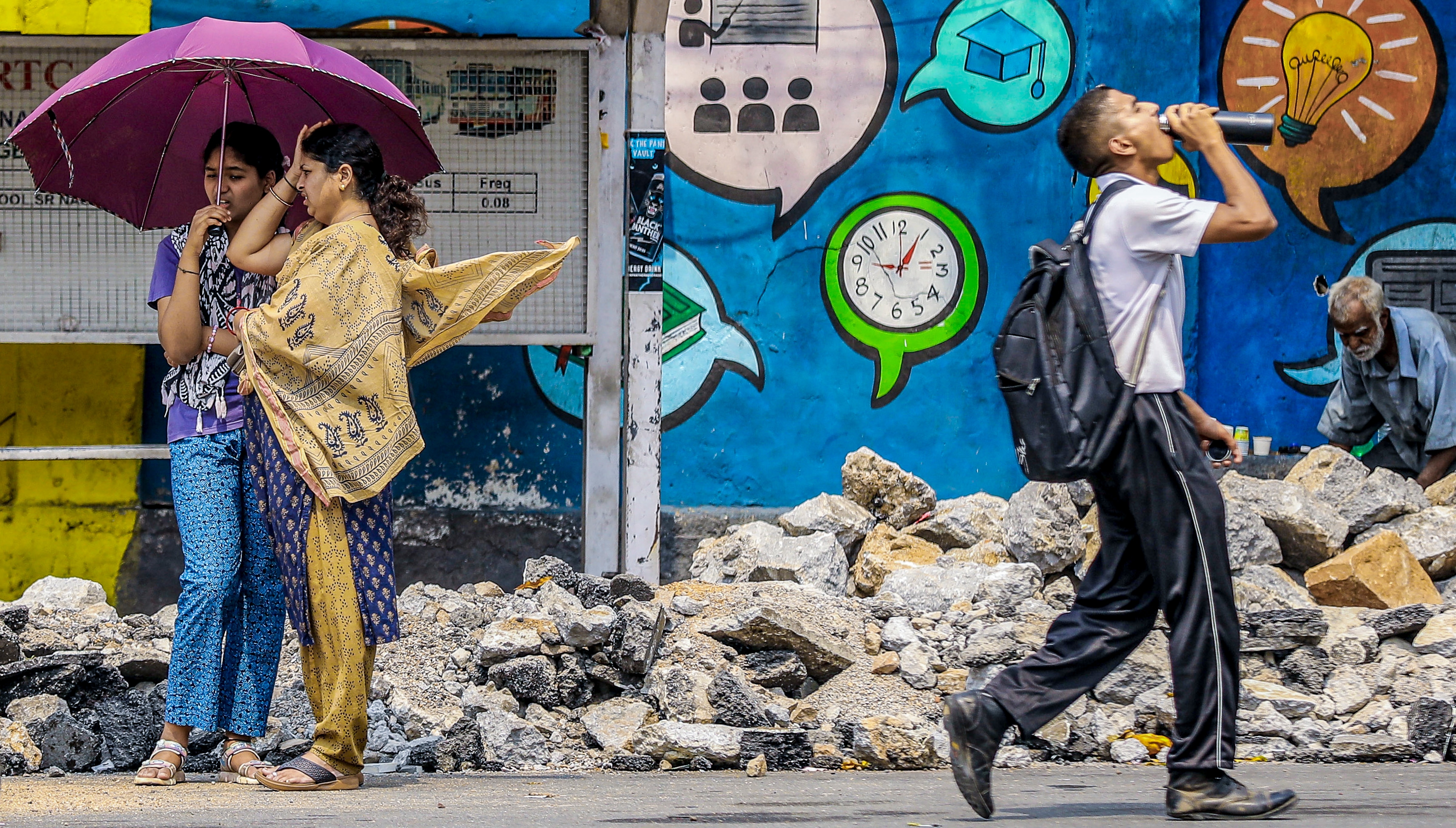 People use an umbrella and drink water to cope with the heat on a summer day. (Photo: PTI)