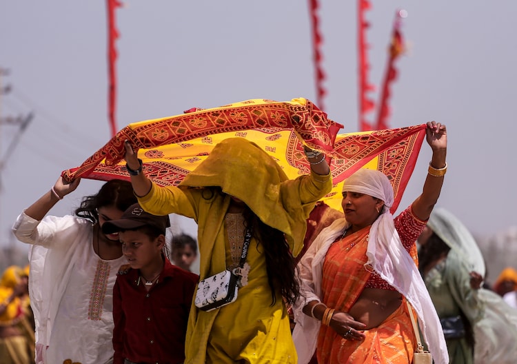 People shield themselves from the scorching heat on the banks of river Ganga. (Photo: PTI)