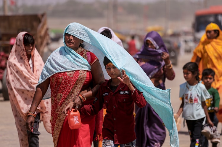 People shield themselves from the scorching heat on the banks of river Ganga. (Photo: PTI)