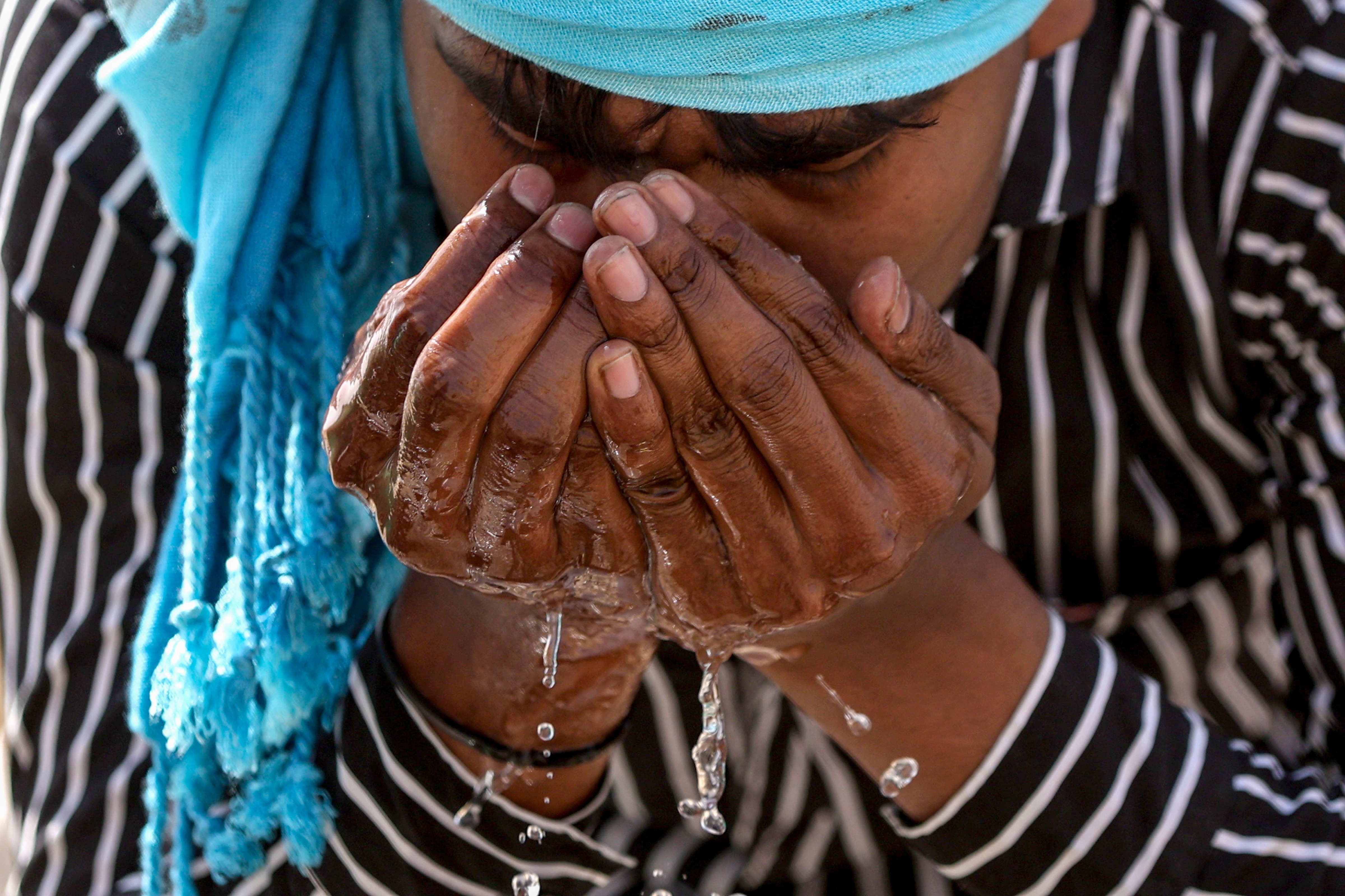 A man drinks water from a tap on a hot summer day, in Prayagraj. (Photo: PTI)
