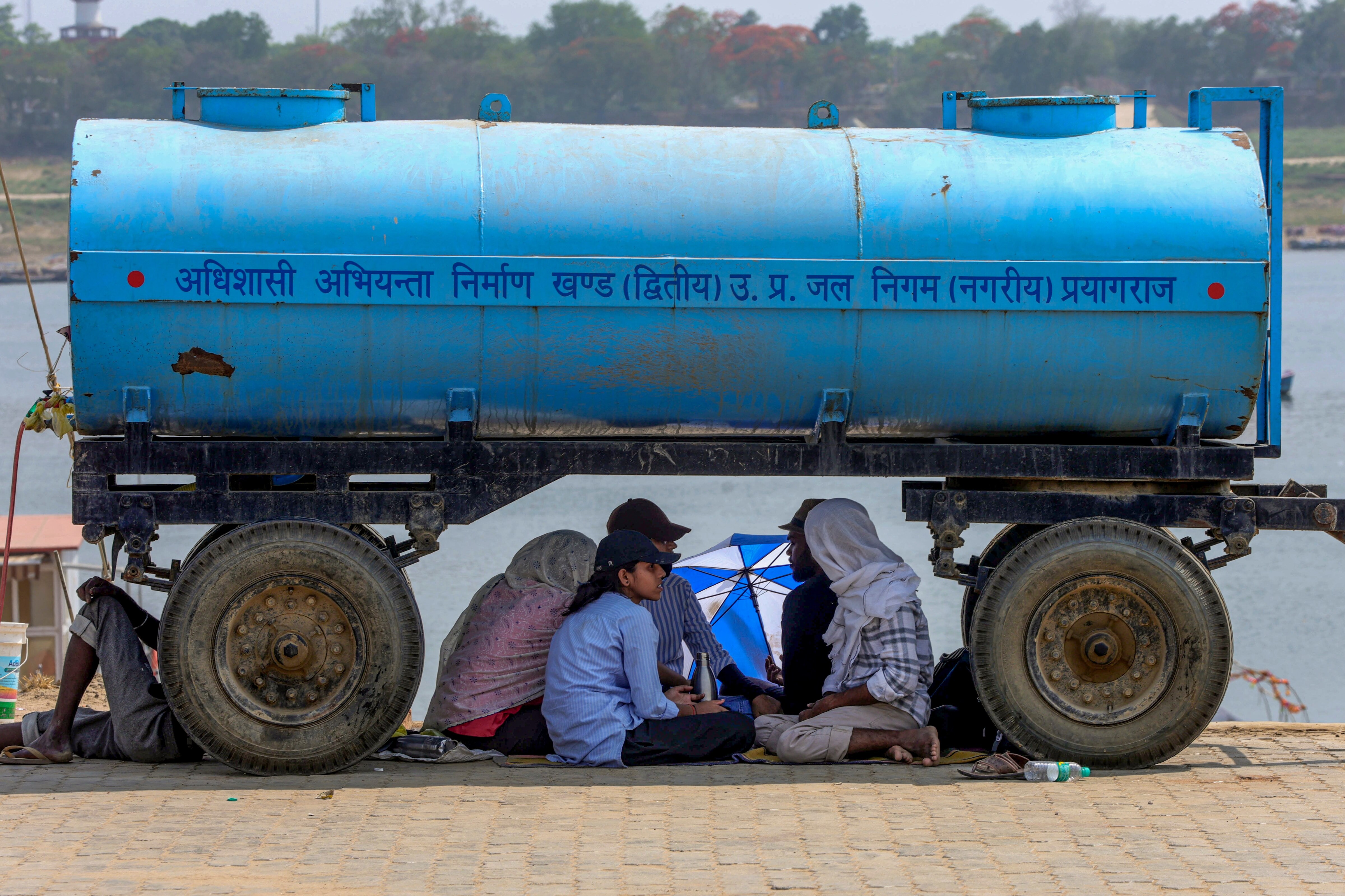 People sit under the shade of a water tanker on a hot summer day. (Photo: PTI)