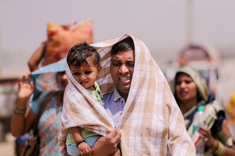 A man covers a kid and himself on a hot summer day, in Prayagraj, Uttar Pradesh. (Photo: PTI)