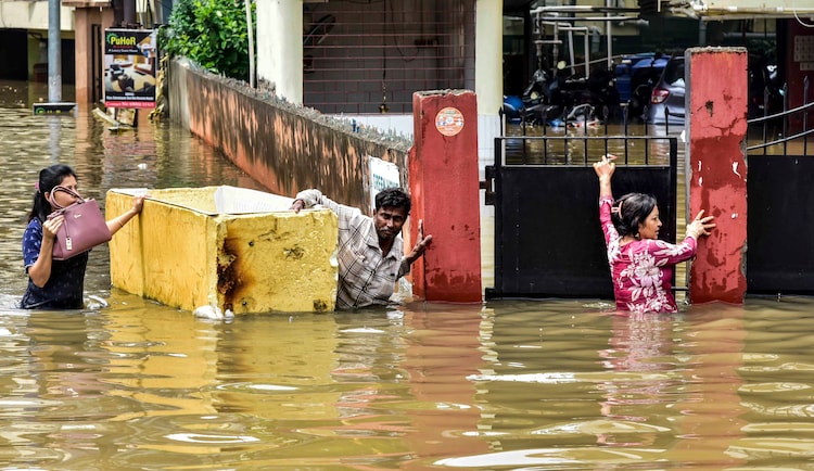 People wade through a waterlogged area after heavy rainfall, in Guwahati, Assam. (Photo: PTI)