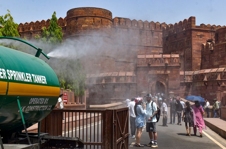 A municipal water sprinkler tanker sprays water to beat the heat in Agra. (Photo: PTI)
