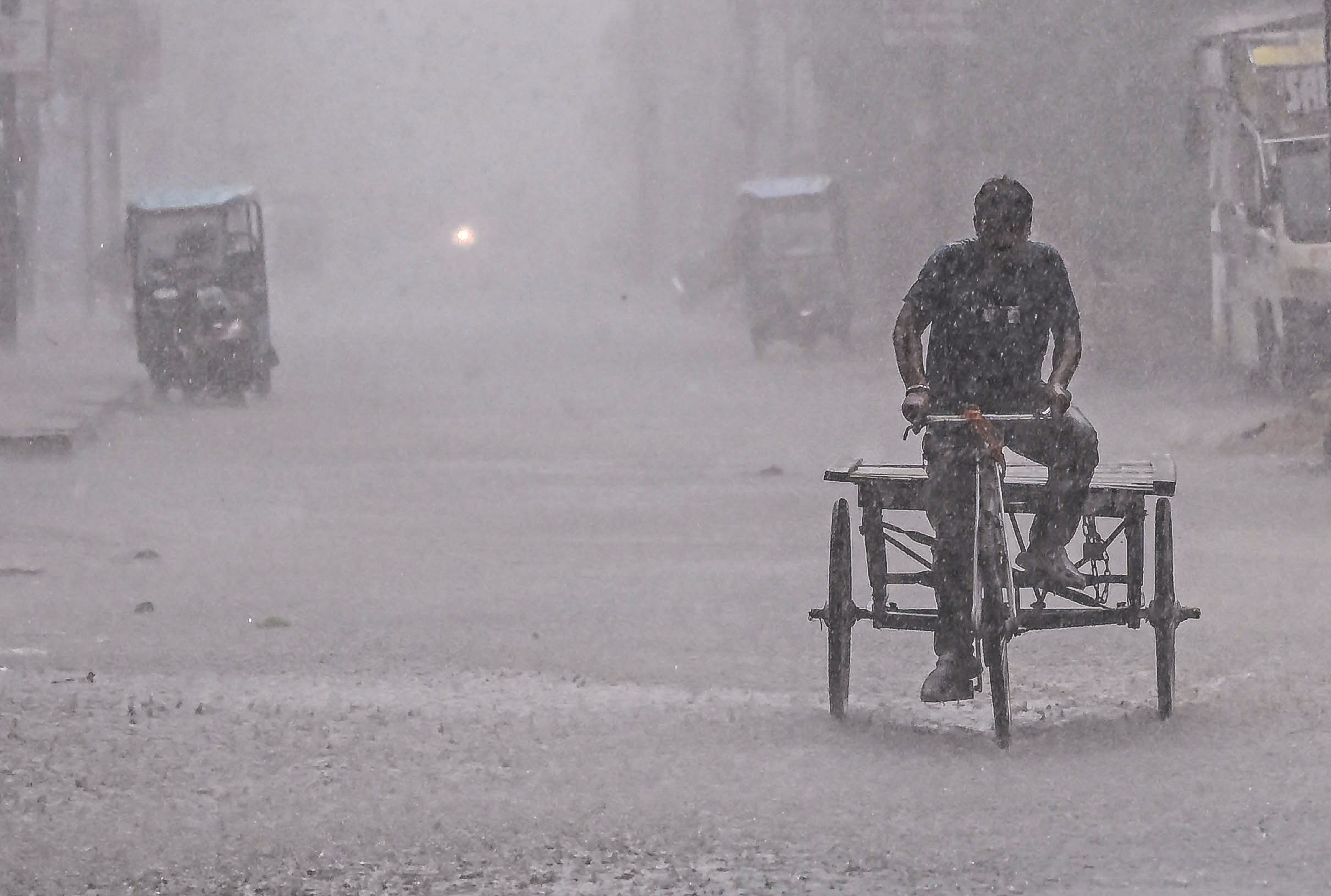  A man rides a cycle-rickshaw through a waterlogged street during heavy rain. (Photo: PTI)