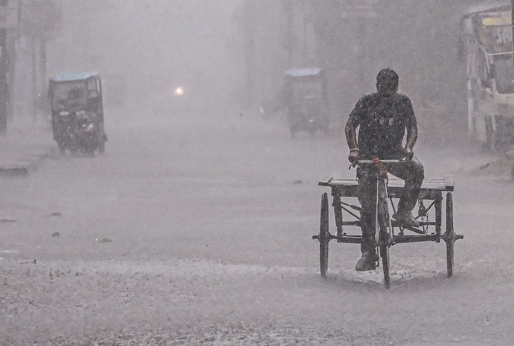Rain on its way: Monsoon on track to hit India, strong signals from Australia A man rides a cycle-rickshaw through a waterlogged street during heavy rain. (Photo: PTI)