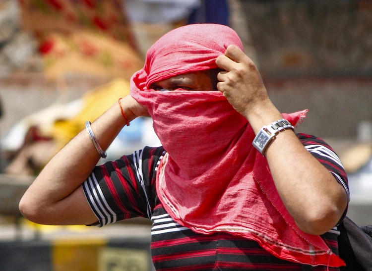 A commuter adjusts scarf on his face on a hot summer day, in Gurugram. (Photo: PTI)