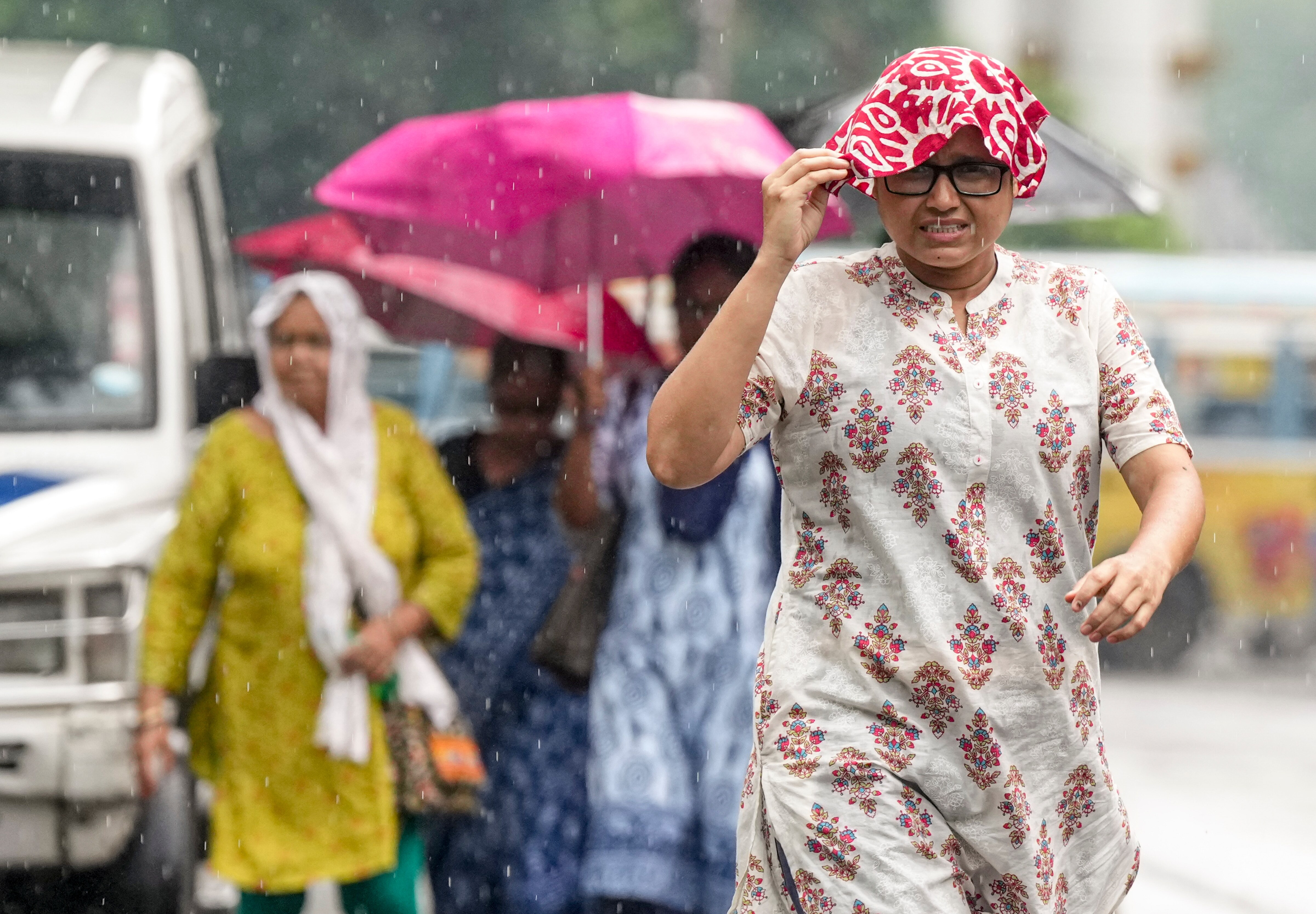 People cover themselves as they walk during rainfall, in Kolkata. (Photo: PTI)