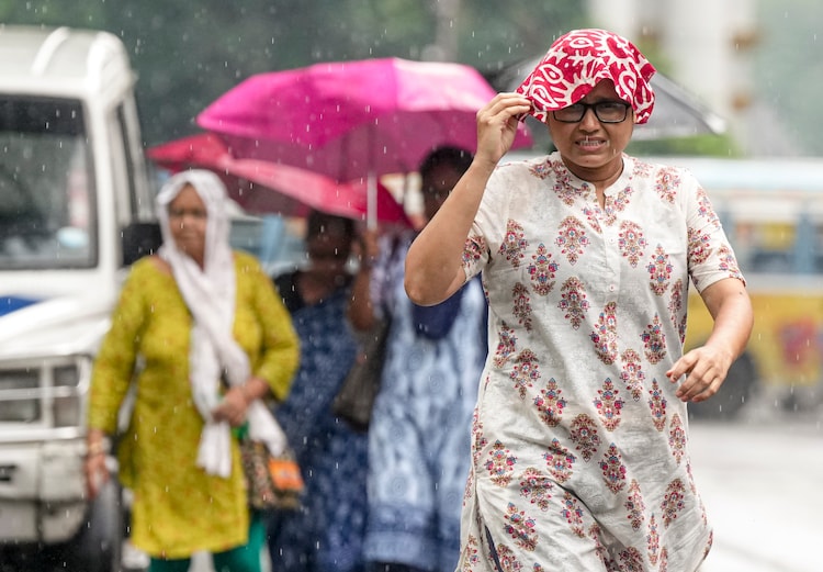 People cover themselves as they walk during rainfall, in Kolkata. (Photo: PTI)