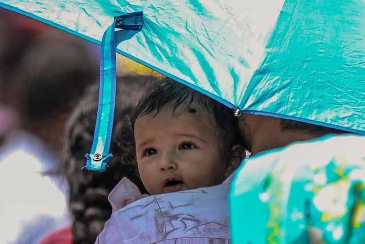 A man shields a baby from a scorching Sun on a hot day in Delhi. (Photo: PTI)