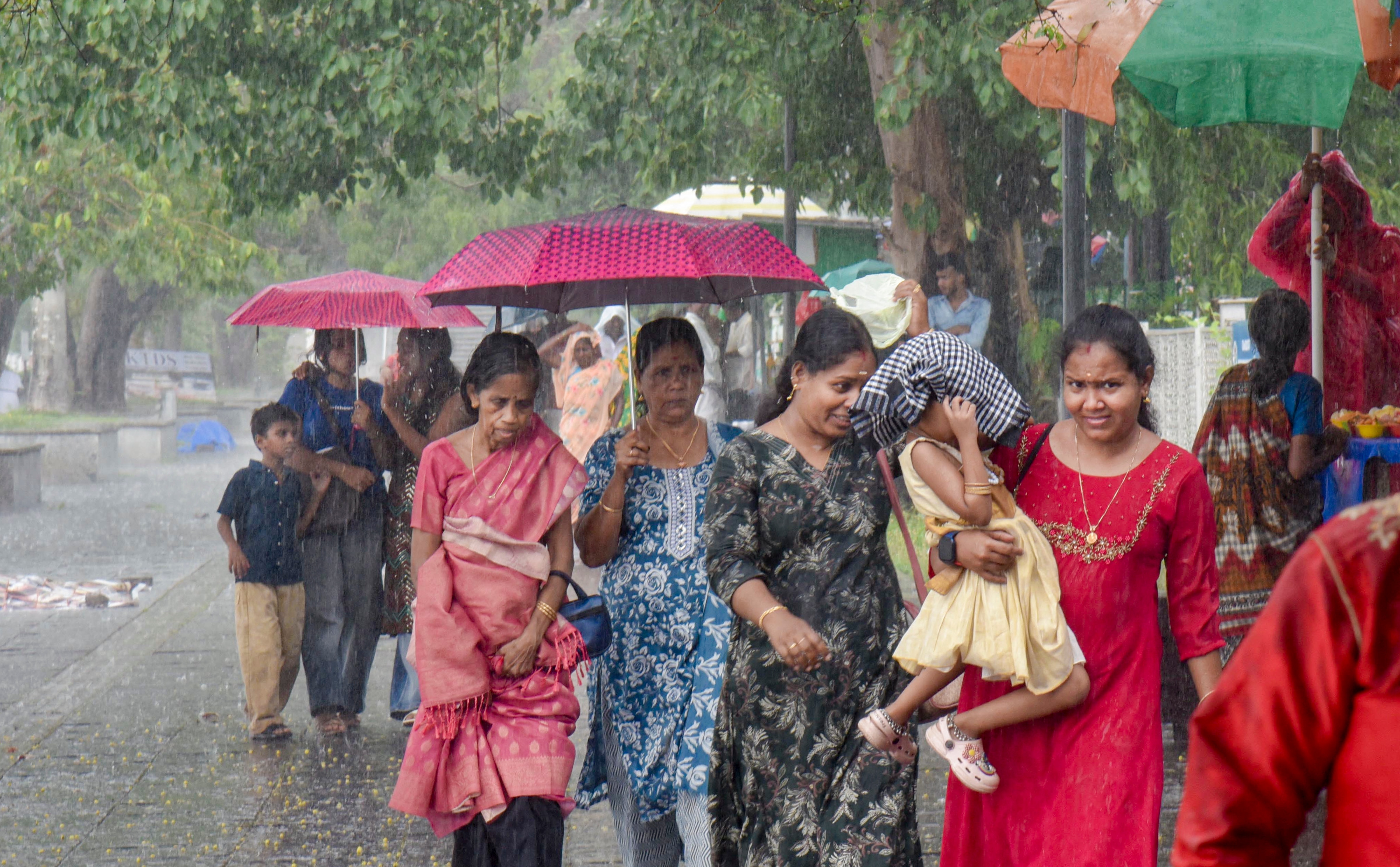 Women cover themselves while walking amid rainfall, in Kochi, Kerala. (Photo: PTI)