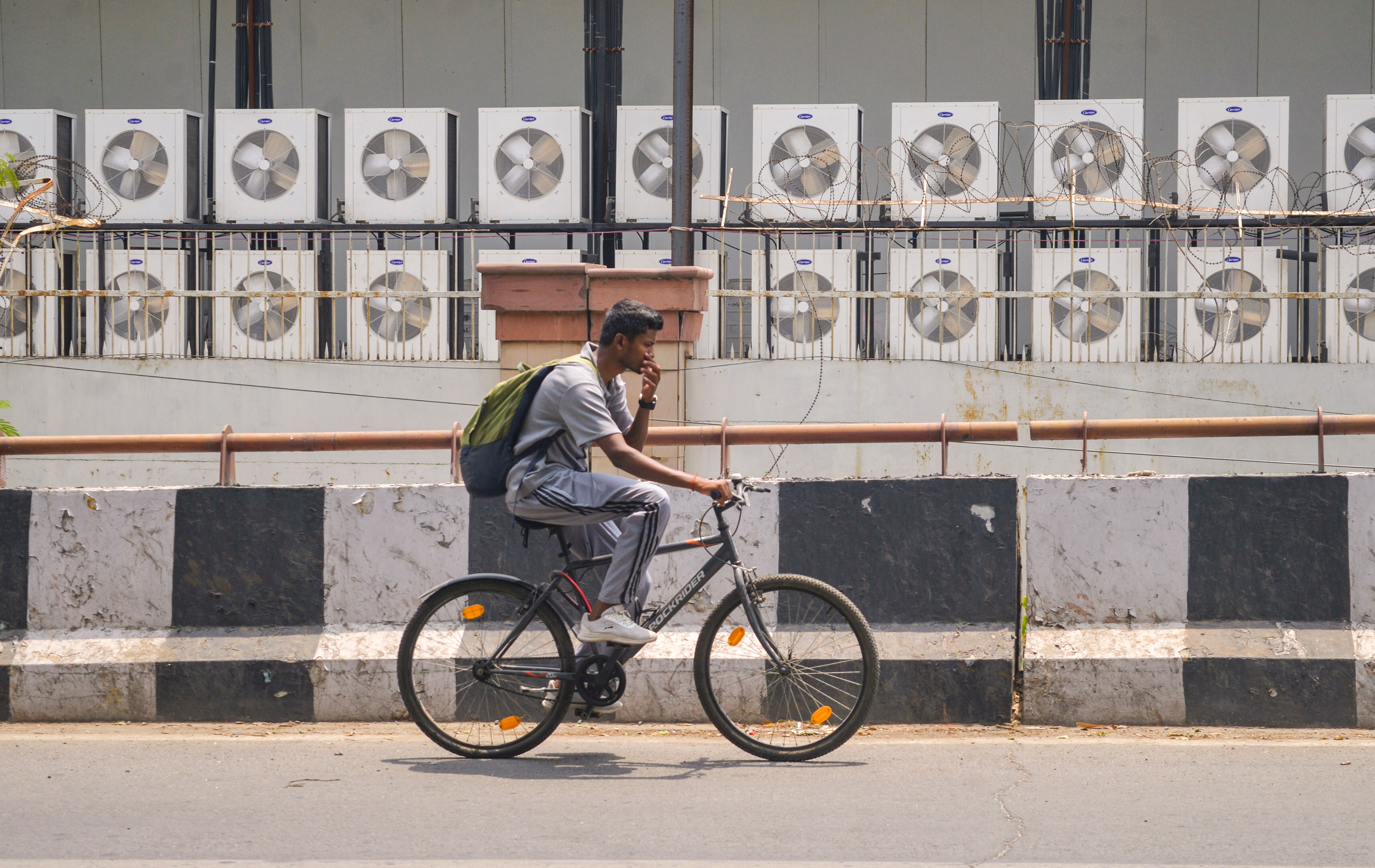 A man cycles past multiple air conditioner units at a commercial space. (Photo: PTI)