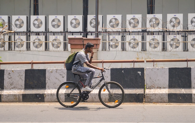 A man cycles past multiple air conditioner units at a commercial space. (Photo: PTI)
