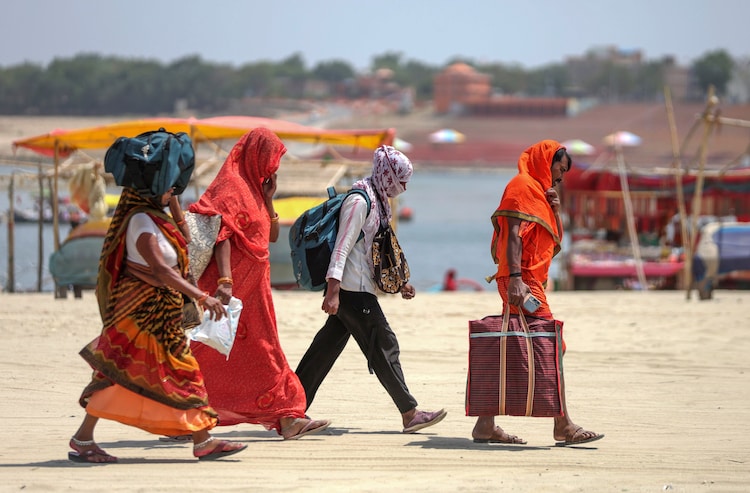 People walk with their faces covered to protect themselves from the heatwave. (Photo: PTI)