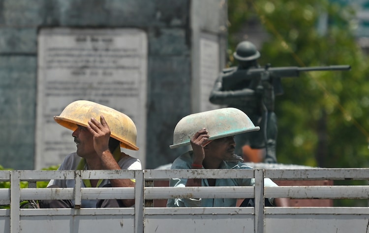 Workers cover themselves from the scorching heat during summer season, in Prayagraj, Uttar Pradesh. (Photo: PTI)